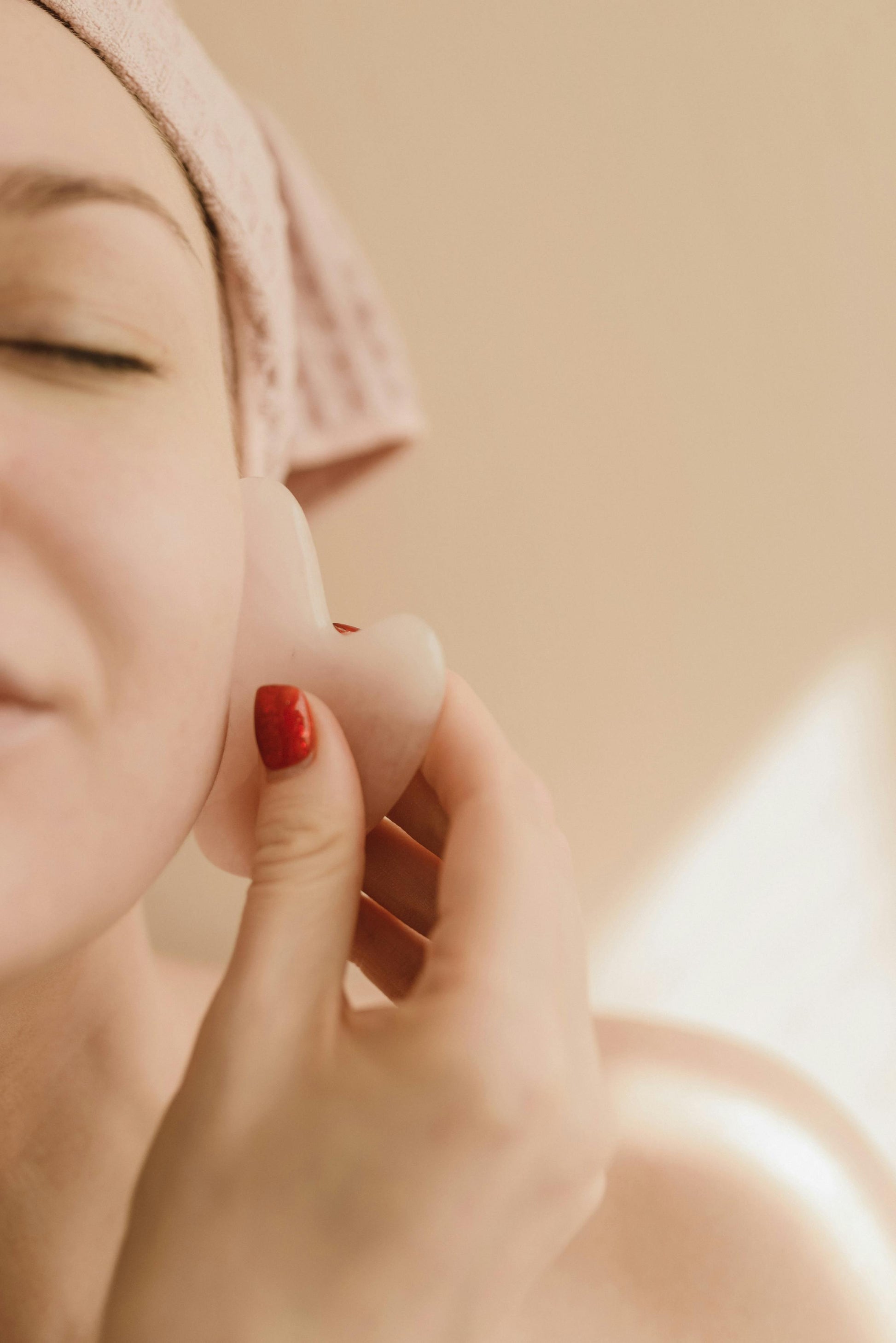 Close-up of a person applying cream to their face with Skin Of Light Products