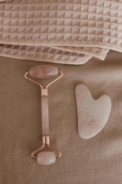 Gua Sha tool and roller on a textured beige surface
